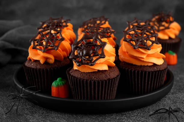 istock Halloween chocolate cupcakes with orange frosting and chocolate spider web on a dark background. Festive dessert. Funny food idea. Copy space. 2171970853