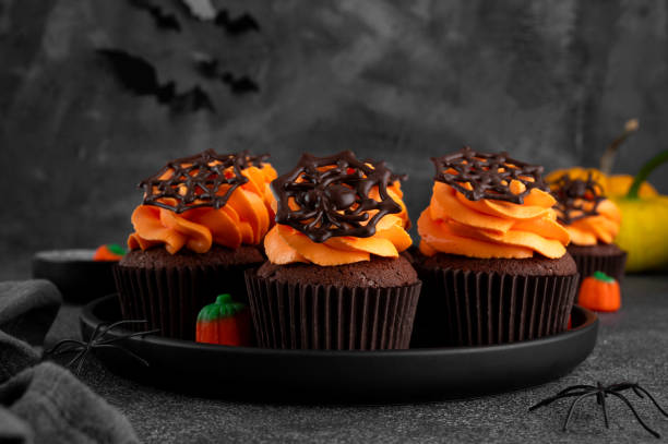 istock Halloween chocolate cupcakes with orange frosting and chocolate spider web on a dark background. Festive dessert. Funny food idea. Copy space. 2171970876