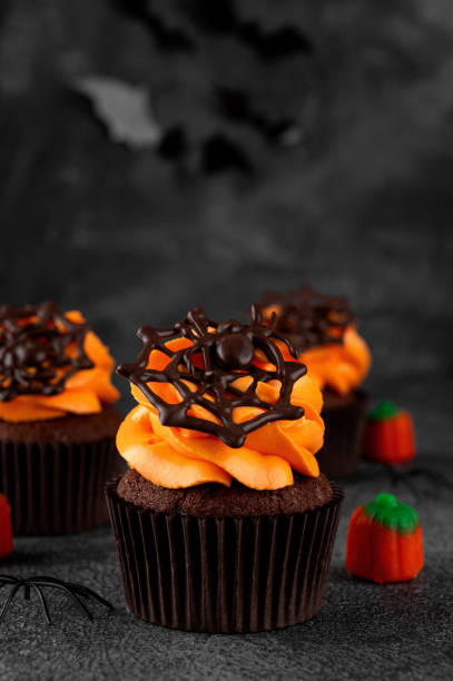 istock Halloween chocolate cupcakes with orange frosting and chocolate spider web on a dark background. Festive dessert. Funny food idea. Copy space. 2171970884