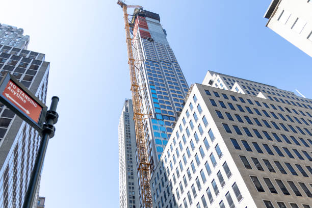 istock Urban development scene featuring the construction of a high-rise building with a crane against a clear sky in a bustling city environment. 2171974628