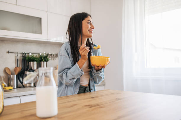 istock A young cheerful woman eating cornflakes for breakfast in the kitchen. 2171981822