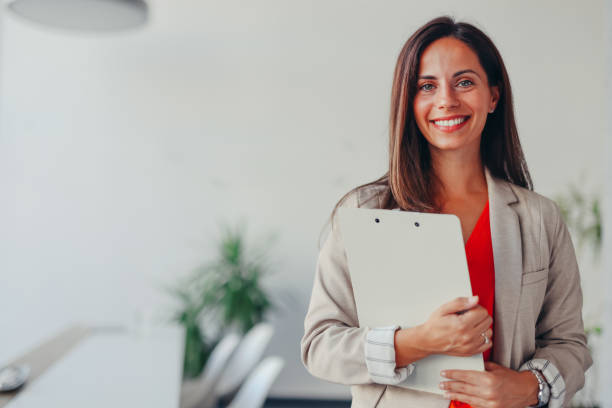 istock Smiling businesswoman standing in office with clipboard 2171992003