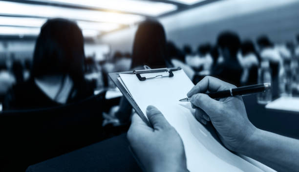 People writing on document at a business seminar