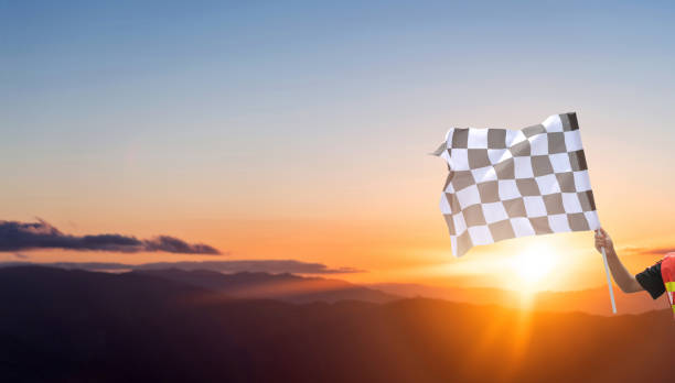 Checkered race flag in hand against sunset sky