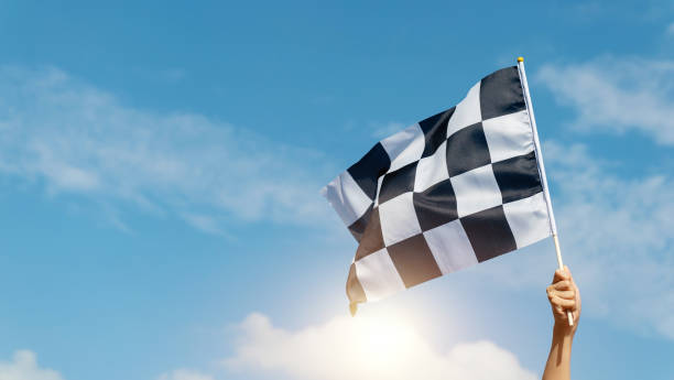 istock Checkered race flag in hand against blue sky 2171992803