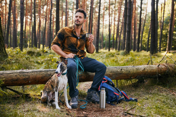 istock Man with dog enjoying autumn hike in forest taking break drinking coffee 2171993296