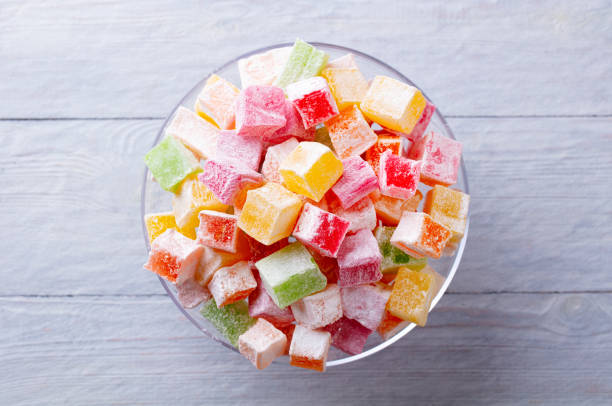 Assorted Turkish delights on glass cake stand, bowl. Grey background. Close up. Top view.