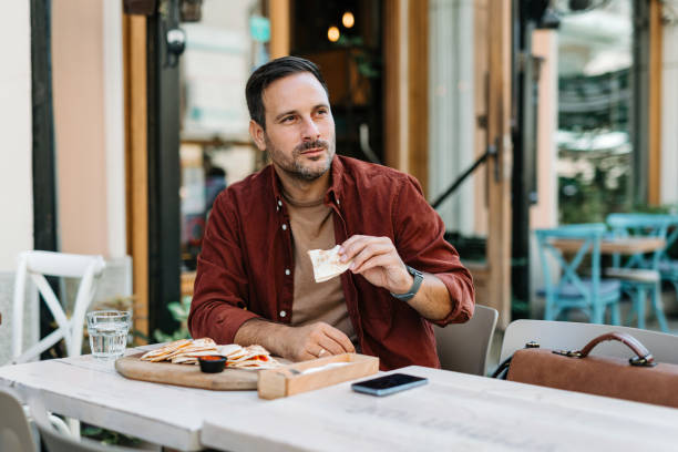 istock Man with relaxed expression eating quesadilla outdoors. 2172005872