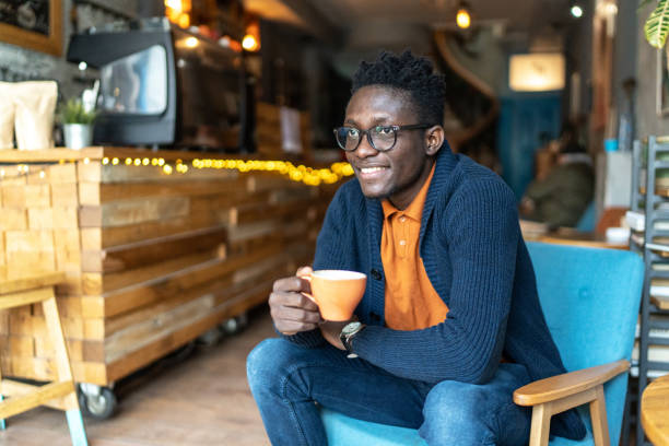 istock Young black man sitting in cafe and drinking coffee 2172013844