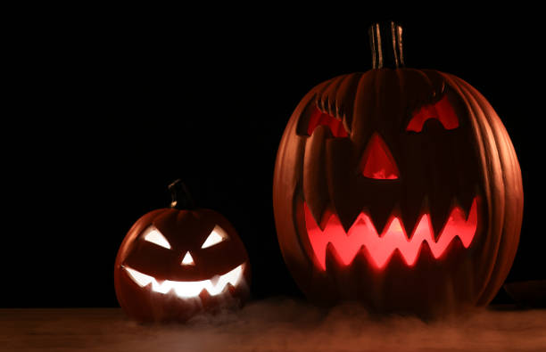 Spooky Halloween pumpkins, Halloween Jack-o-Lantern Pumpkins, Jack O Lantern with evil faces and eyes isolated against a dark background.