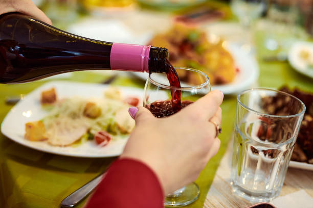 istock hand holds a glass into which red wine is pouring from a bottle 2172024135