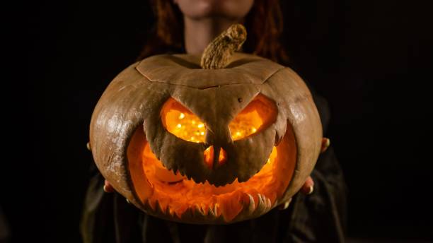 istock The witch is holding a pumpkin jack about a lantern glowing in the dark. Halloween. 2172028596