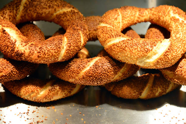 Istanbul, Turkey: Turkish bagels / pretzels, called simit in Turkey and koulouri or gevrek in neighbouring countries - Simit is a popular Turkish bread, often described as a cross between a bagel and a pretzel. It is round in shape with a crispy crust covered in sesame seeds and a chewy, soft interior. Simit is a staple in Turkish cuisine, commonly enjoyed as a snack or breakfast item, often accompanied by tea, cheese, olives, or jam. It has a rich history, dating back to the Ottoman Empire, and is now widely available in street vendors, bakeries, and cafes across Turkey and other parts of the Middle East and Europe. Its simple yet flavorful nature makes it a beloved and iconic food item.