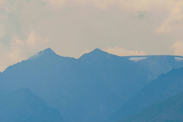 A view of distant mountain peaks partially covered in mist, creating a serene and atmospheric landscape.