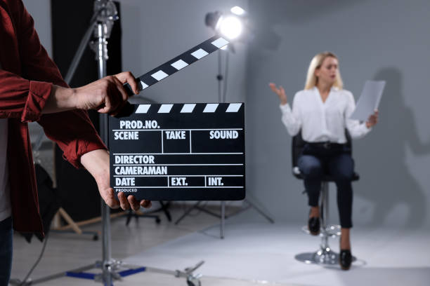 istock Casting call. Emotional woman performing while second assistance camera holding clapperboard against grey background in studio, selective focus 2172042977