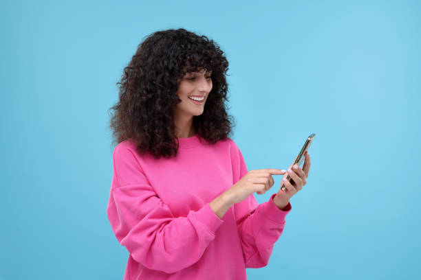 istock Woman sending message via smartphone on light blue background, space for text 2172043070