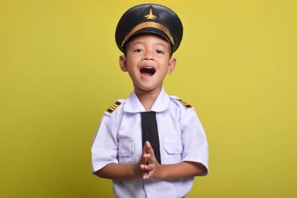 Little Asian boy Airplane pilot posing welcoming arrival isolated on yellow background. Little boy dreams of becoming an airplane pilot