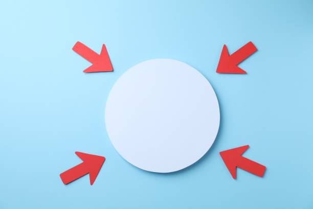 Red paper arrows and white circle on light blue background, flat lay. Space for text
