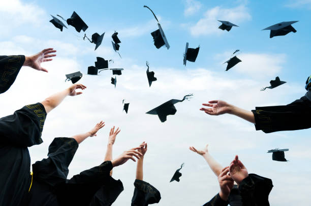 istock Graduating students hands throwing graduation caps in the air 2172051002