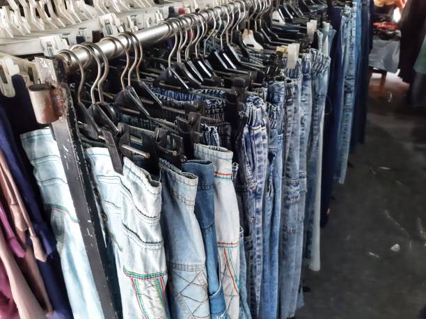 Detail view of neatly hung clothing on metal rack with creative workshop and wooden shelving softly blurred in the background.