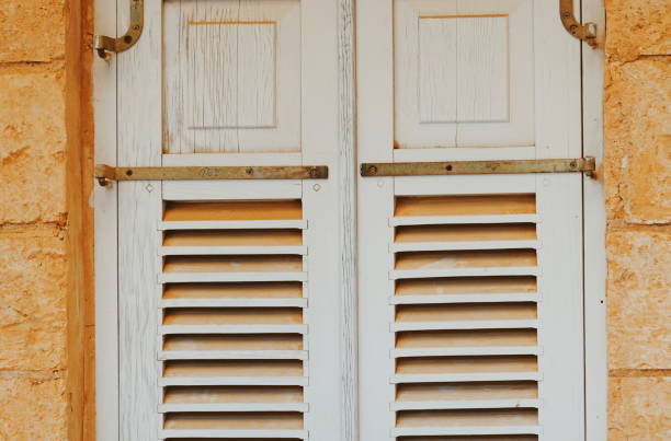 istock Vintage White Wooden Shutters On Orange Stone Wall Front View 2172065469