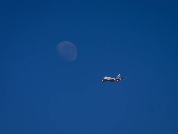 Vacoas, Mauritius - July 25, 2024 : A388 Emirates jet airliner flight UEA702 destination Mauritius flying in clear blue sky with moon in background