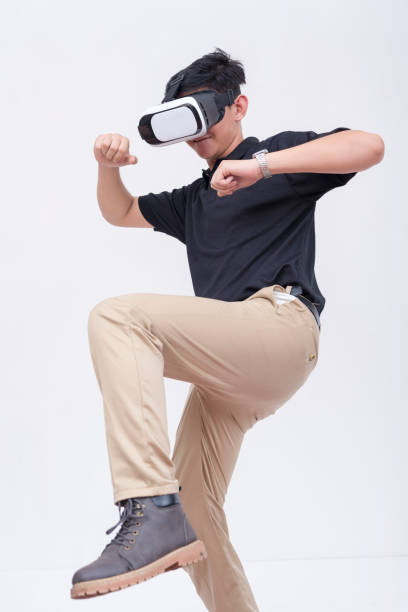 A young man playing a VR fighting game via a virtual reality headset. Isolated on a white backdrop.