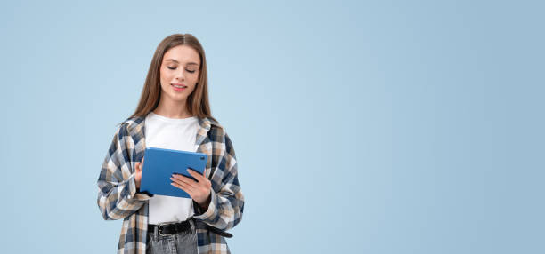 istock Woman reading a tablet with blue background and copy space.. 2172072442