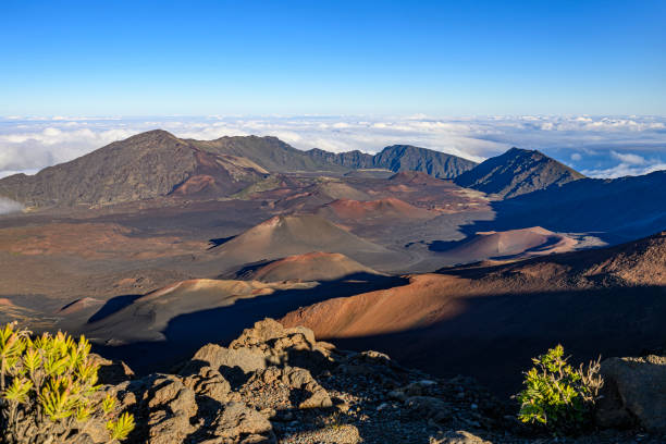 Volcanic landscape with some smaller craters of dormant volcanoes inside the huge Haleakala Crater (10020 ft tall) in Maui, Hawaii in the evening.