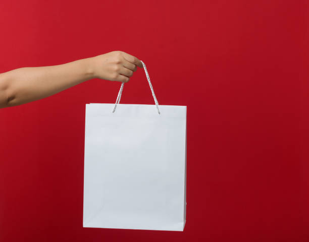 istock Female hand holding a shopping bag. Red background. 2172078081
