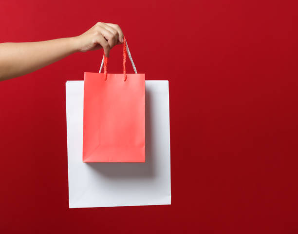 istock Female hand holding a shopping bag. Red background. 2172078085