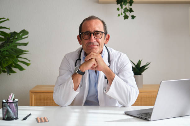 istock Confident doctor smiling at office desk with laptop and stethoscope 2172099984