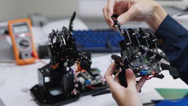 Close-up shot of  engineer hands using simulation  handset remote conrol the simulated robotics hand to moving after input the program to circuit borad and command in laboratory room.