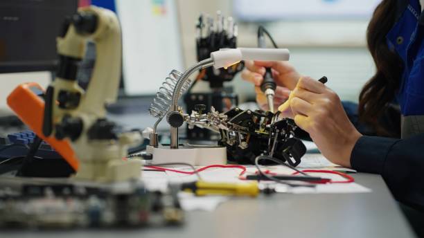 istock Close-up at electrical engineerhand use the soldering the lead with IC chip at circuit board. She work in the laboratory room. 2172101061