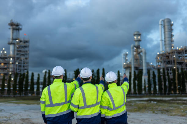 istock Team professional electrical engineer safety uniform working together power plant or station refining oil petrochemical evening time. Industrial factory site control energy power station. 2172104972