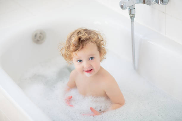 istock Little baby in bath tub playing with soap foam 2172105367