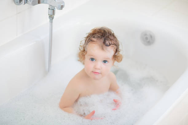 istock Little baby in bath tub playing with soap foam 2172105499