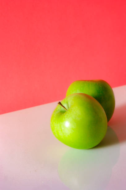 Stock photo showing close-up view of a red apple made into a cartoon character with googly eyes on top of a group of green Granny Smith apples with shiny, speckled skin. Fun way to encourage healthy eating in children.