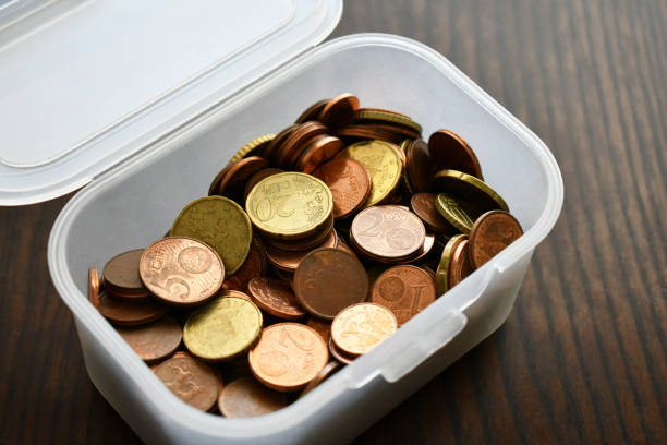 Euro cent coins in a plastic box. Savings concept. Old coins on wood table.