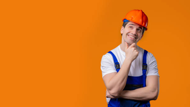 istock Thinking around mature handyman worker or builder man on orange. Copy space. 2172124218