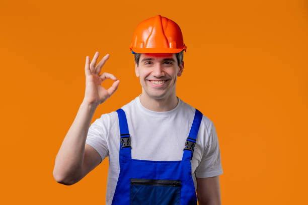 istock Positive builder in helmet, protective uniform makes OK okay hand sign on orange 2172124220