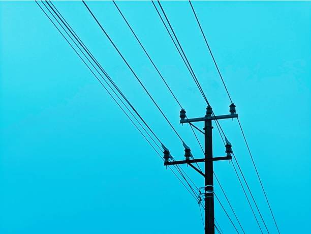 istock Silhouette of a power pole with cables stretching across a bright blue sky. 2172126144