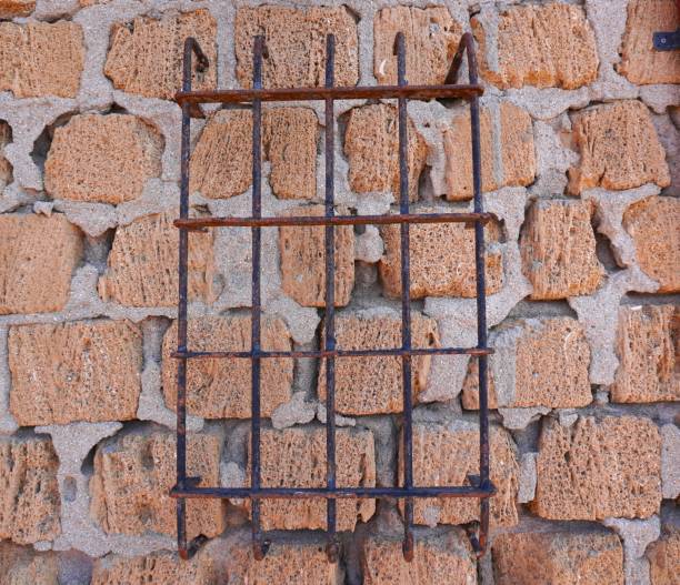 Old metal grate. Old rusty grate on an old wall made of shell stones.