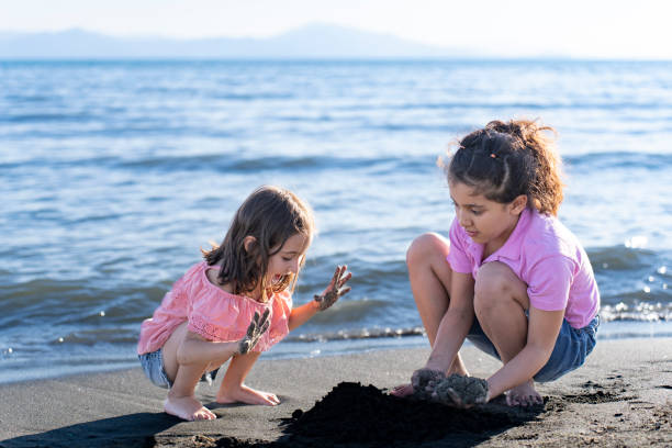 Children playing with sand by the sea.