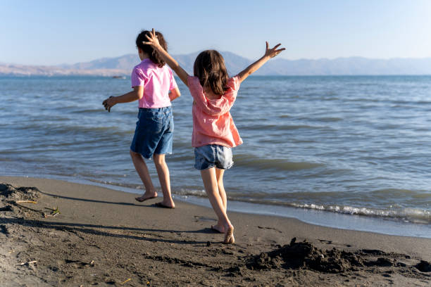 Children playing with sand by the sea.