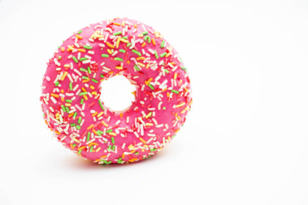 A brightly lit image of a single pink-glazed doughnut adorned with matching pink sprinkles, set against a neutral backdrop