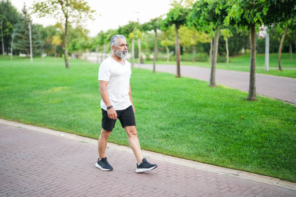 istock white haired and bearded man walking in the park 2172140294