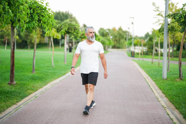 istock white haired and bearded man walking in the park 2172140778