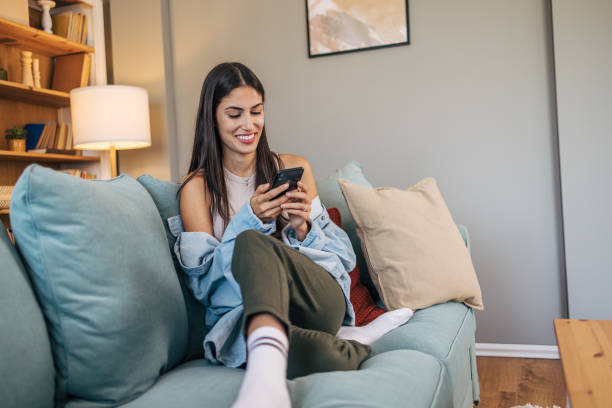istock A young cheerful woman relax on sofa and using smartphone. 2172146332
