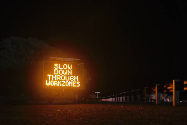 istock Slow down through work zones, night time illuminated road warning sign. Australia Outback. Rural roads. Road death toll. Copy space against night sky. 2172147381